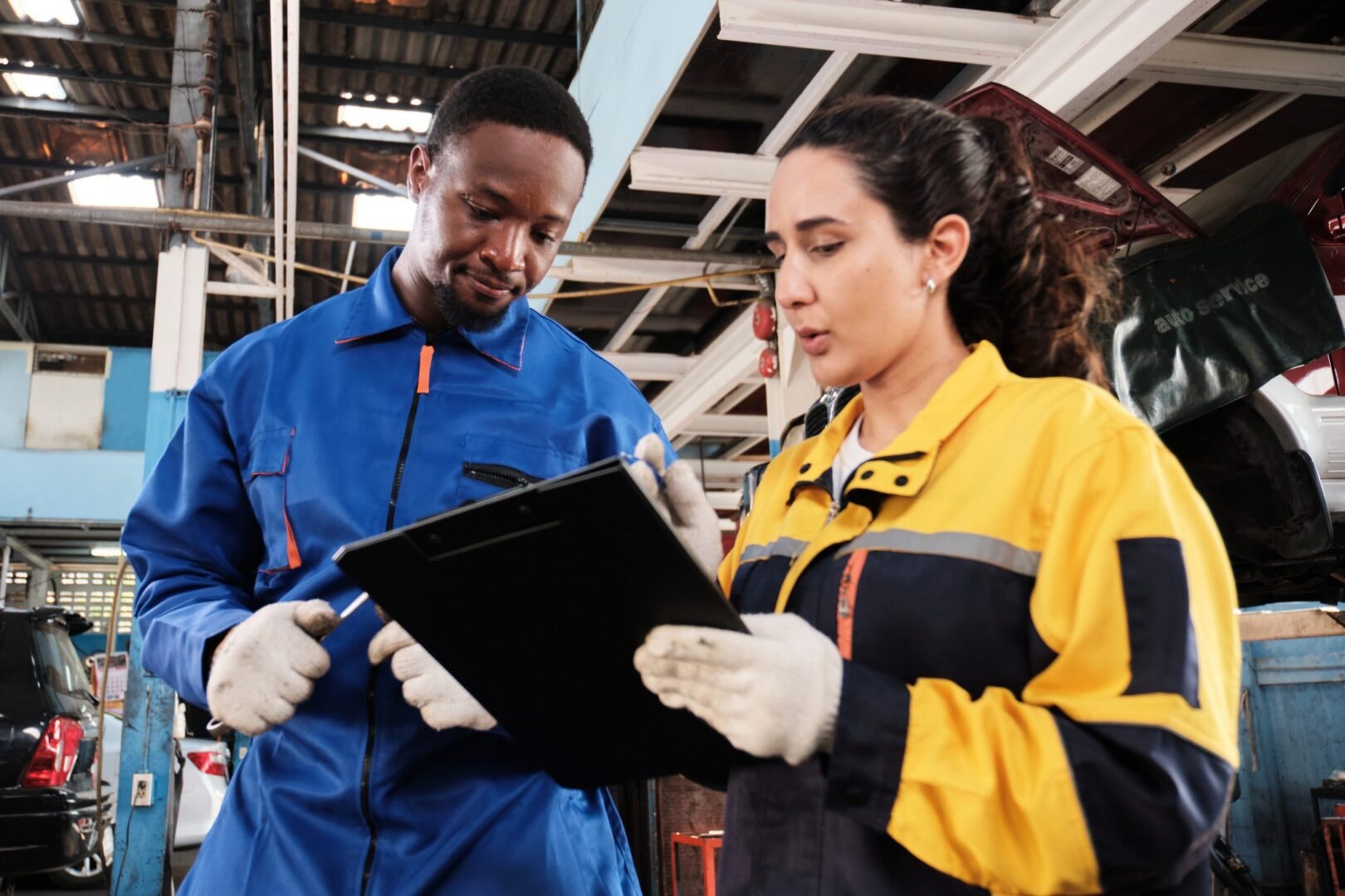 Two manufacturing workers in safety gear reviewing a clipboard together